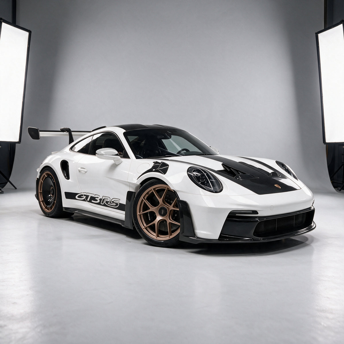 Porsche 911 GT3 RS (992) in white with bronze wheels and rear carbon aero discs, wearing the full Carbon District dry carbon body kit, front three-quarter in the studio